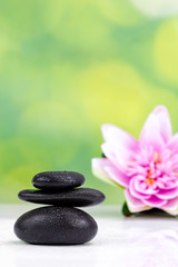 Naklejka na ściany i meble Balanced zen stones with drops of water on a green bokeh background