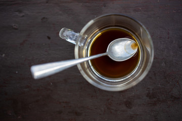 Glass coffee cup, finished americano coffee drink left over and siver spoon on wooden table background, Close up shot, Selective focus