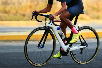 close up of a road cyclist riding a white carbon frame holding the bike handlebar during a road race competition,
