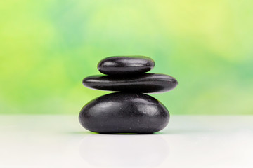 Balanced zen stones with drops of water on a green bokeh background