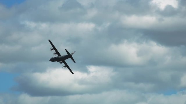 C-130 Hercules military airplane makes sharp baking turn in slow-motion. Tracking shot.