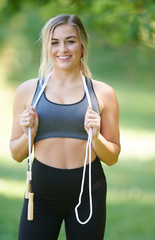 Fototapeta premium Stunning young blonde woman working out in summer heat - jump rope - fitness