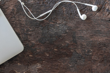 Top view laptop and earphone on old wooden background with copy space