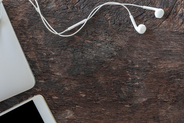 Top view laptop, smartphone and earphone on old wooden background with copy space