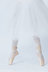 A girl stands on outstretched legs, shod in pointe shoes. A child in a white dress for dancing and...