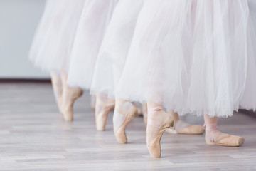 Feet in pointe. Exercises in the ballet school. Ballet classes. A group of girls standing in a row,...