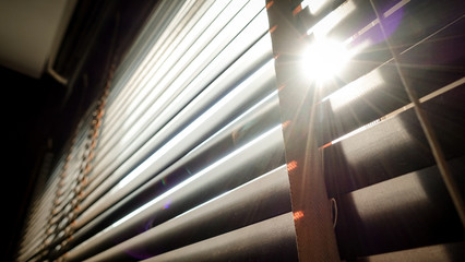 Naklejka premium evening sun light outside with wooden window blinds, sunshine and shadow on window blind, decorative interior home concept 
