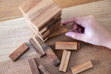 Closeup image of a hand holding and playing Tumble tower wooden block game