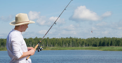a man in a hat, on the background of beautiful nature, engaged in fishing