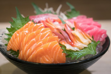 Mixed sliced fish sashimi on ice in black bowl. Sashimi Salmon Tuna Hamachi Prawn and Surf Calm...