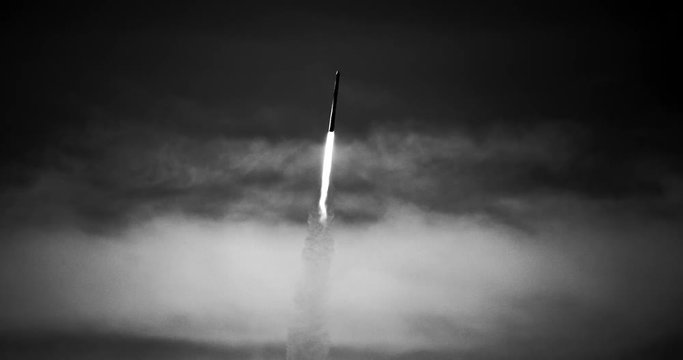 B&W footage (recreation) of cold war era ICBM missile rocket flying into space with exhaust flames, heat trail, and smoke in 4K.