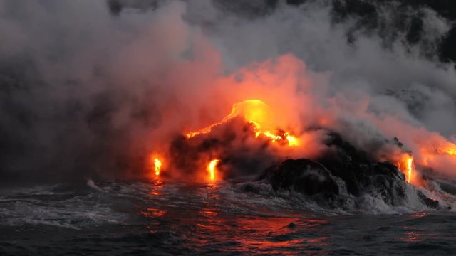 Lava flowing into the ocean from lava volcanic eruption on Big Island Hawaii, USA. Lava stream flowing in Pacific Ocean from Kilauea volcano around USA. Seen from water, Steadicam, 59.94 FPS.