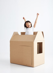 Asian little girl playing with paper house, in white background
