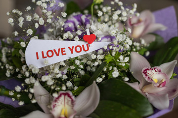 Flowers and card with inscription love you. Valentines Day background and love message. Love...