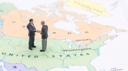 Miniature people, businessman standing on map American