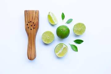 Limes with wooden lime squeezer on white.