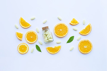 Vitamin C bottle and pills with orange fruit on white. - obrazy, fototapety, plakaty
