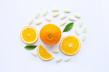 Vitamin C pills with orange fruit on white.