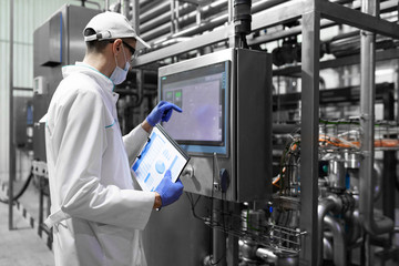 technologist taking necessary notes while standing at production department of dairy factory