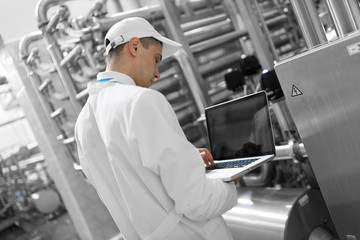 Technologist with a laptop in his hands at the dairy plant