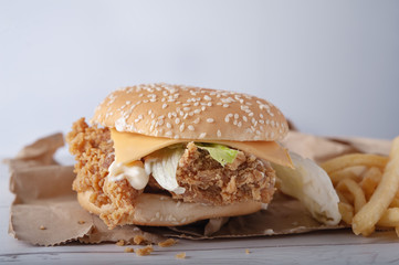 Crispy chicken burger with cheese and mayonnaise sauce on wooden table background