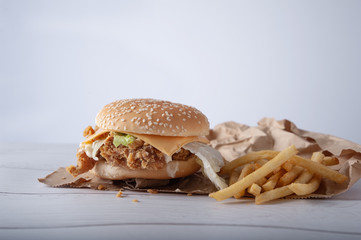 Crispy chicken burger with cheese and mayonnaise sauce on wooden table background