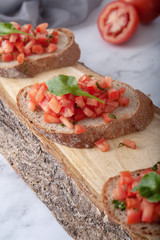 Bruschetta sandwiches with tomato, basil leaf and garlic on wooden board as background