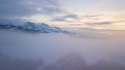 Fototapeta na wymiar Aerial mountain winter landscape. Fantastic morning clouds glowing by sunlight.