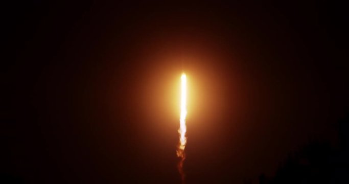 Rocket lifting off at night with trees in foreground &permil;&Ucirc;&Oacute; exhaust flames and smoke. 120 fps slow motion.