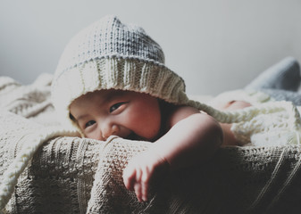 Portrait of smiling baby boy wearing knit hat lying in basket