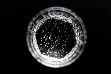 Top view of sparkling water in transparent glass on black background.