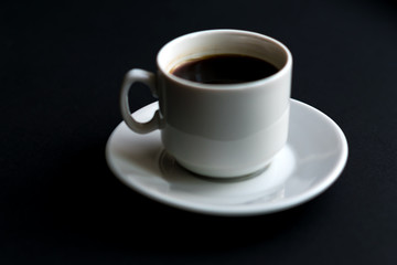 close up of white cup of coffee on black background. Soft focus