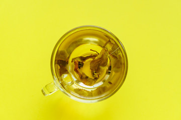 top view of transparent cup with green tea on yellow background.