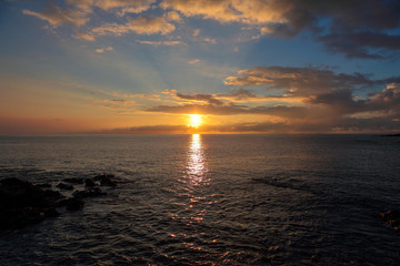 Fototapeta premium Scenic sunset over Pacific Ocean, Big Island, Hawaii. Sun ray color white clouds in red and orange leaving a sparkling path on an ocean surface
