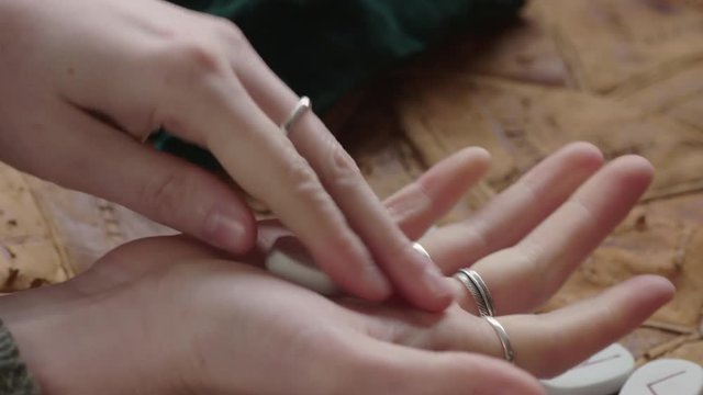 Young woman's hands clasp and turn over a smooth white rune-stone