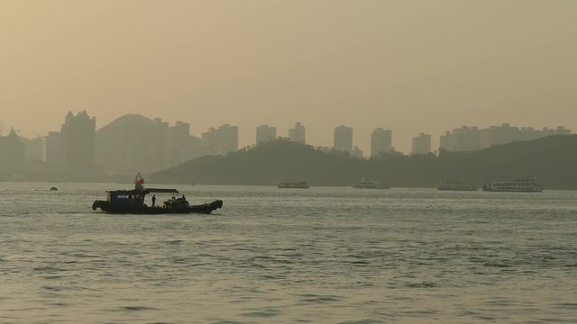 A fishing boat carrying goods sailing on the sea at sunset.