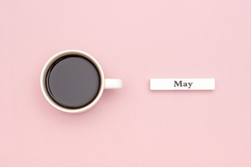 Wooden calendar spring month May and Cup of black coffee on pastel pink paper background. Concept...