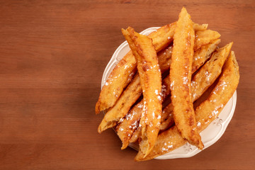 Traditional Spanish porras, a typical Madrid Sunday breakfast, shot from the top on a dark rustic wooden background with copy space