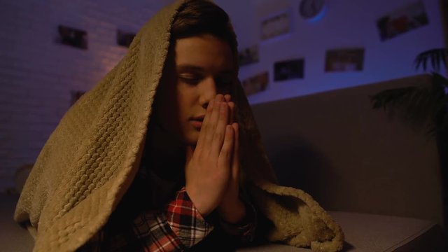 Religious teenager praying covered with blanket, belief in god, sectarianism