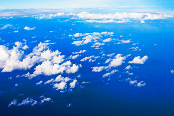 blue sky with cumulus clouds from an airplane window over the pacific ocean