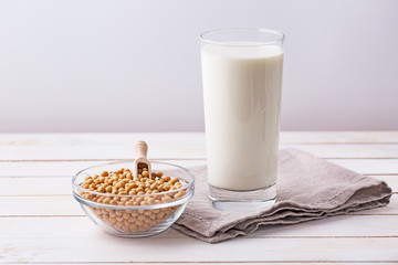 Raw soy seeds and glass of milk on slate background. Organic farming