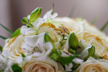 Gold wedding rings lie on a bouquet for the bride. Wedding accessories