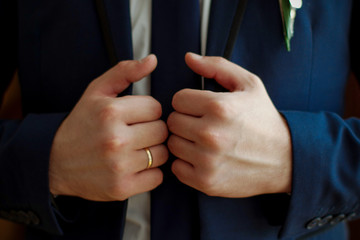 A man holds a jacket collar. Close-up. Wedding day