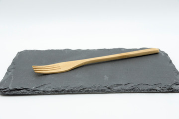 Wooden fork on slate plate on white background