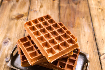 Belgian waffles on a wooden background. Homemade pastries for a family breakfast. Minimal composition. Place for text on the photo.