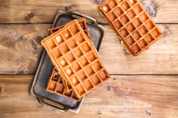 Belgian waffles on a wooden background. Homemade pastries for a family breakfast. Minimal composition. Place for text on the photo.