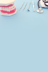 Dental care tools use for dentist and plastic teeth model in the clinic. Wooden blue background.