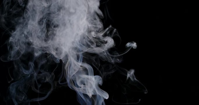 White cloud of vapor rising in slow motion against a black background