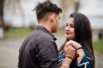 Love story of indian couple posed outdoor, holding hands together.