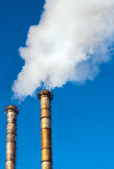 Industrial smoke from chimney on blue sky.